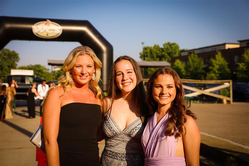Three student-athletes stand together on the red carpet